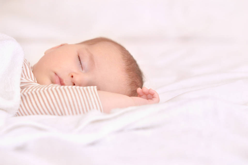 Bébé paisible couché sur un lit tout en dormant dans une chambre lumineuse - Photo, image