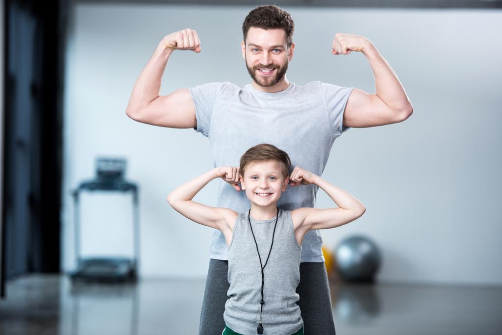 Хлопчик з молодим чоловіком показує м'язи
  - Фото, зображення