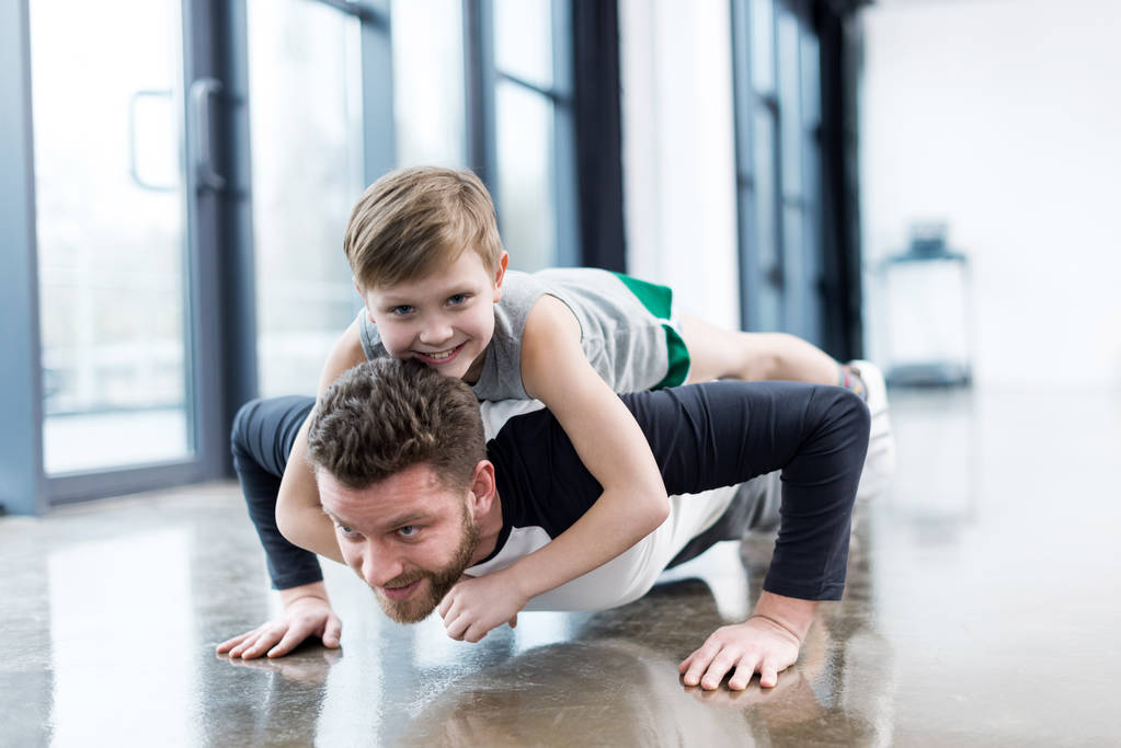 Homem fazendo flexões com menino
  - Foto, Imagem