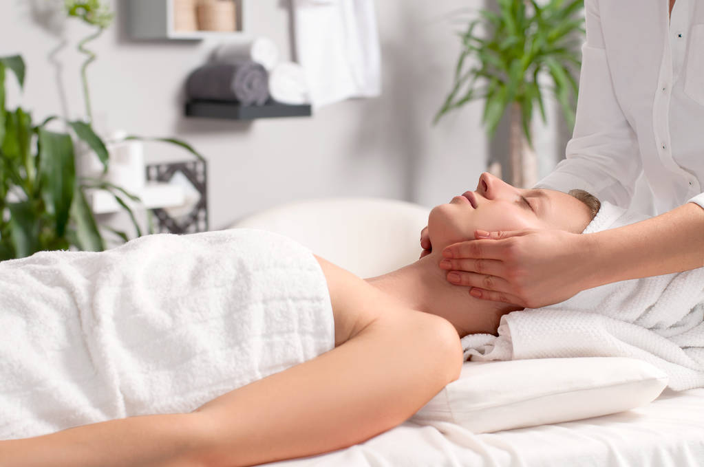 Masér dělá masáž obličeje ženy ve spa salonu - Fotografie, Obrázek