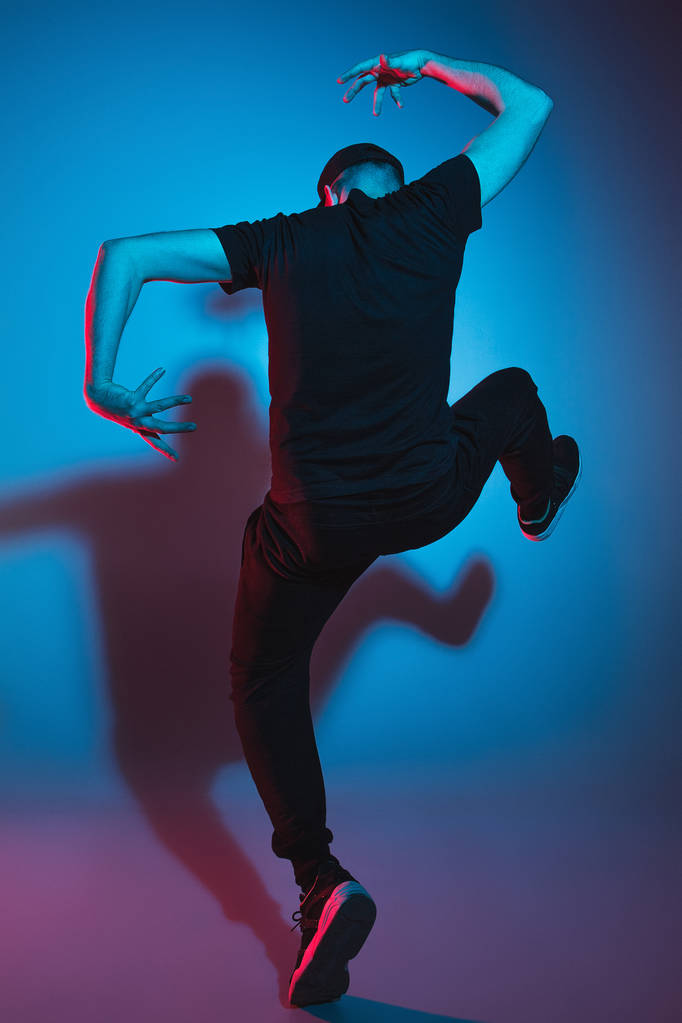 die Silhouette eines männlichen Breakdancers, der auf buntem Hintergrund tanzt - Foto, Bild