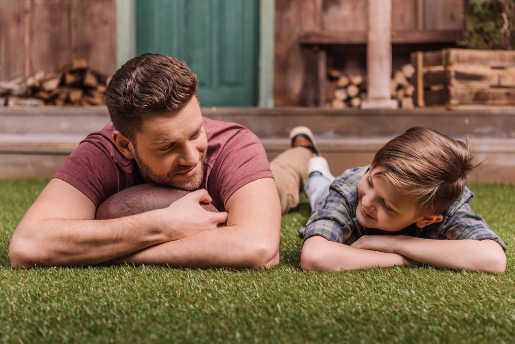 батько з сином лежить на траві
 - Фото, зображення