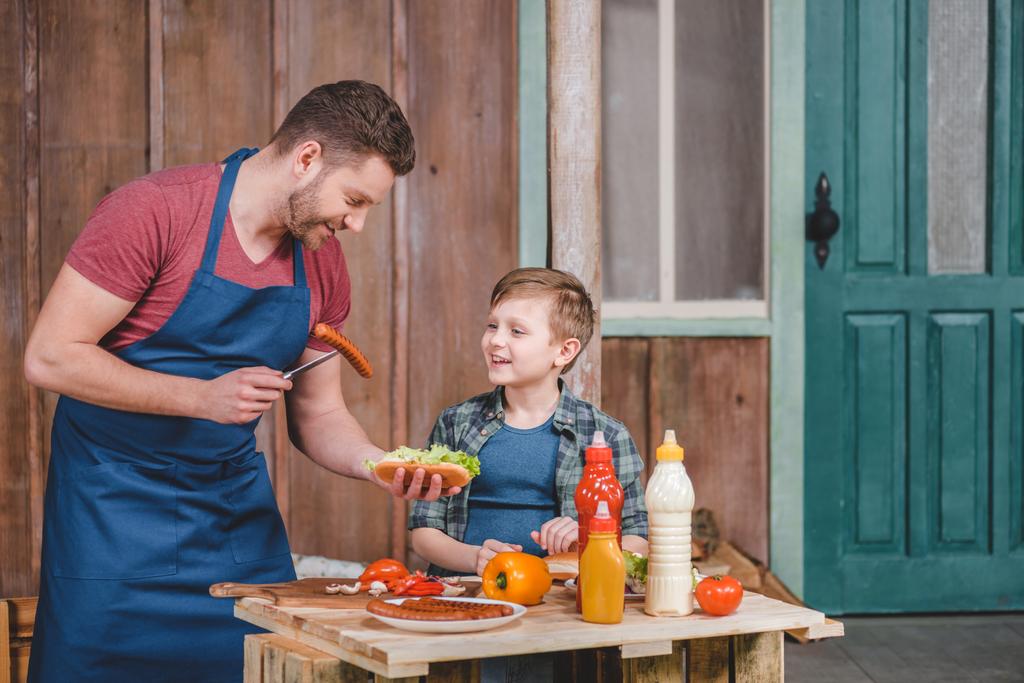 Padre e figlio che cucinano hot dog
  - Foto, immagini