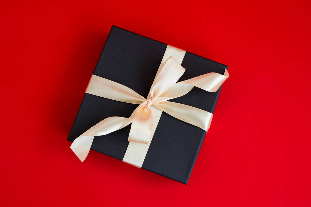 Altın şerit ve bir yay kırmızı zemin üzerine siyah hediye kutusu - Fotoğraf, Görsel