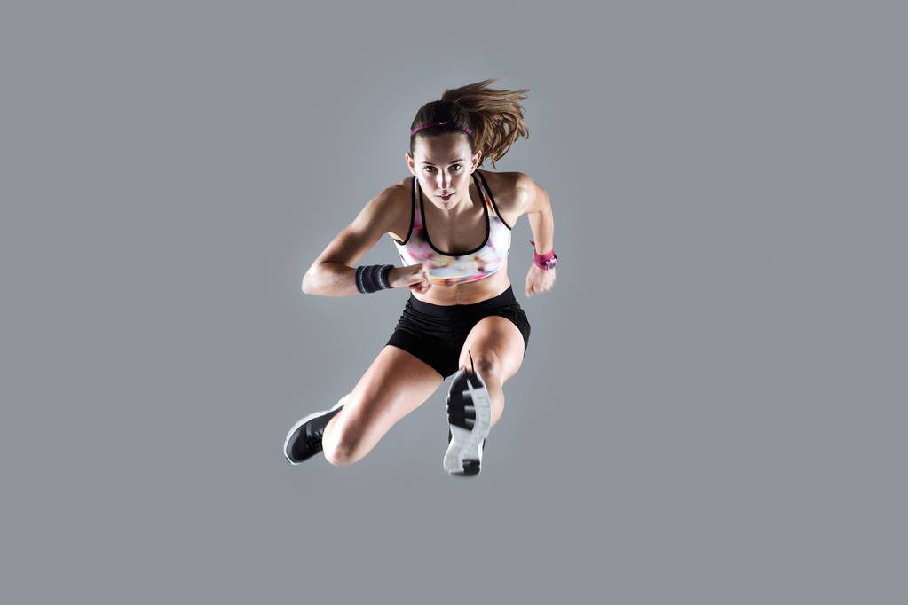 Apto e esportivo jovem mulher pulando no fundo branco
. - Foto, Imagem