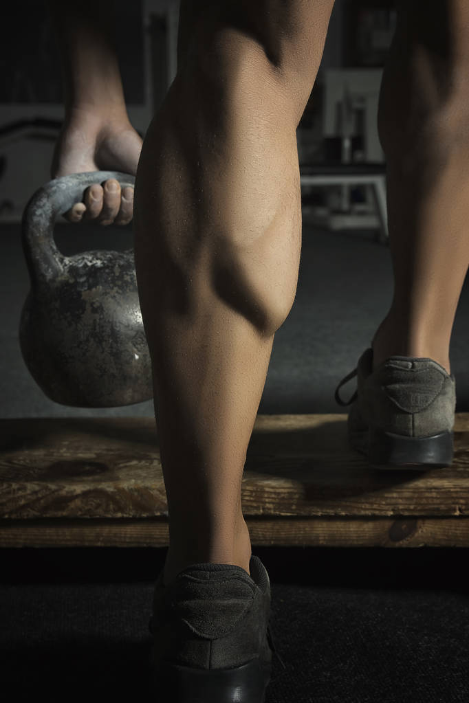Lähikuva lihasten kehonrakentajat jalka tekee harjoituksia painoja
 - Valokuva, kuva