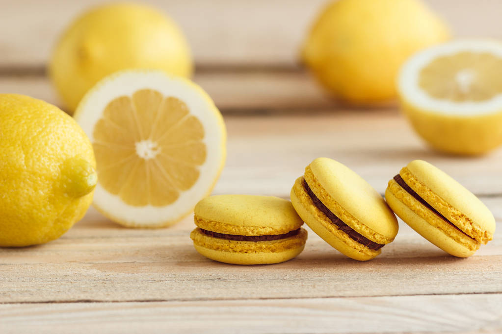gelbe französische Macarons mit Zitronen auf den Holzbrettern - Foto, Bild
