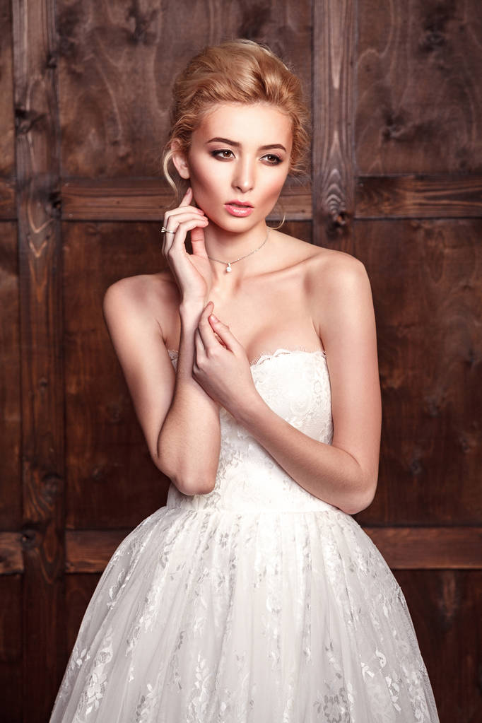 Fashion beauty bridal shooting. Beautiful fashion bride in wedding dress posing in front of woody background. - Photo, Image