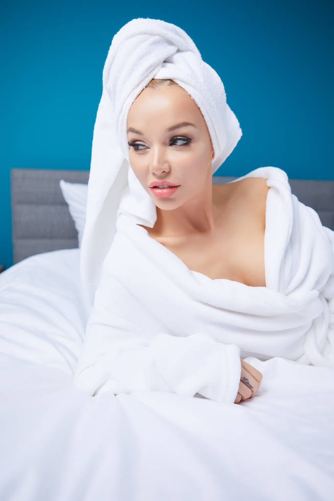 Μια γυναίκα σε ένα μπουρνούζι και μια πετσέτα στο κεφάλι της - Φωτογραφία, εικόνα
