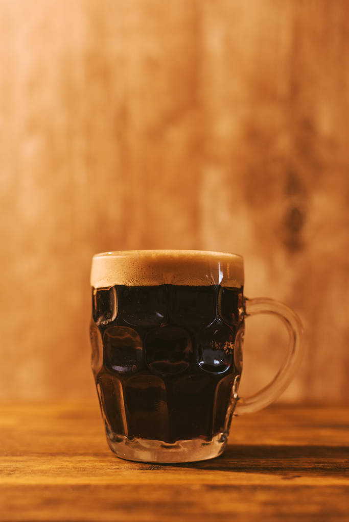 Темное пиво в британской кружке из стеклянной кружки
 - Фото, изображение