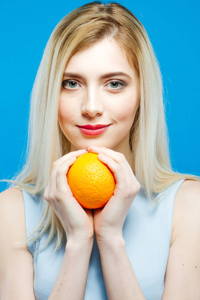 Gyönyörű szőke narancs a kezét a kék háttér stúdióban portré. - Fotó, kép