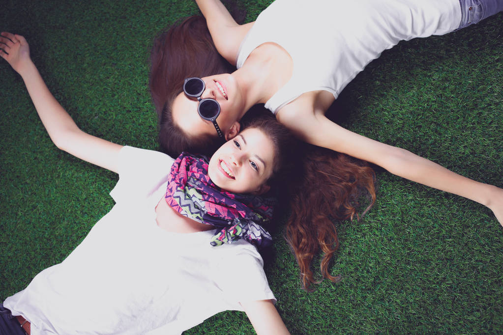 二人の可愛い女の子が緑の草の上に横たわっている - 写真・画像