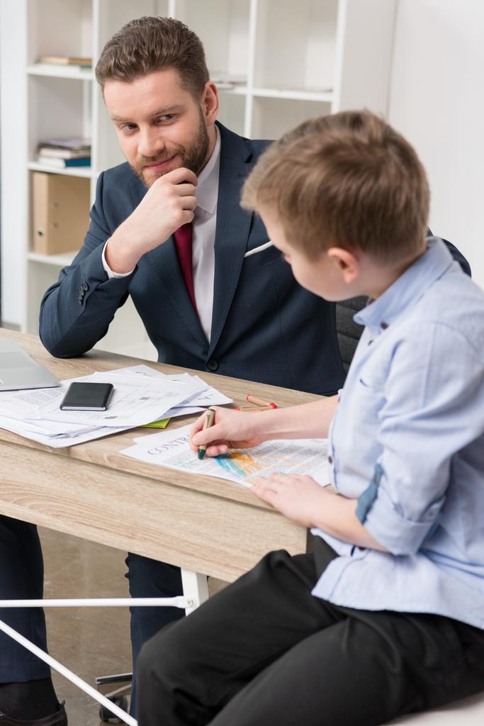 Бізнесмен з сином малює на бізнес-паперах
 - Фото, зображення