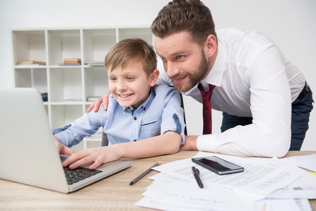 Бизнесмен играет на ноутбуке с сыном
 - Фото, изображение