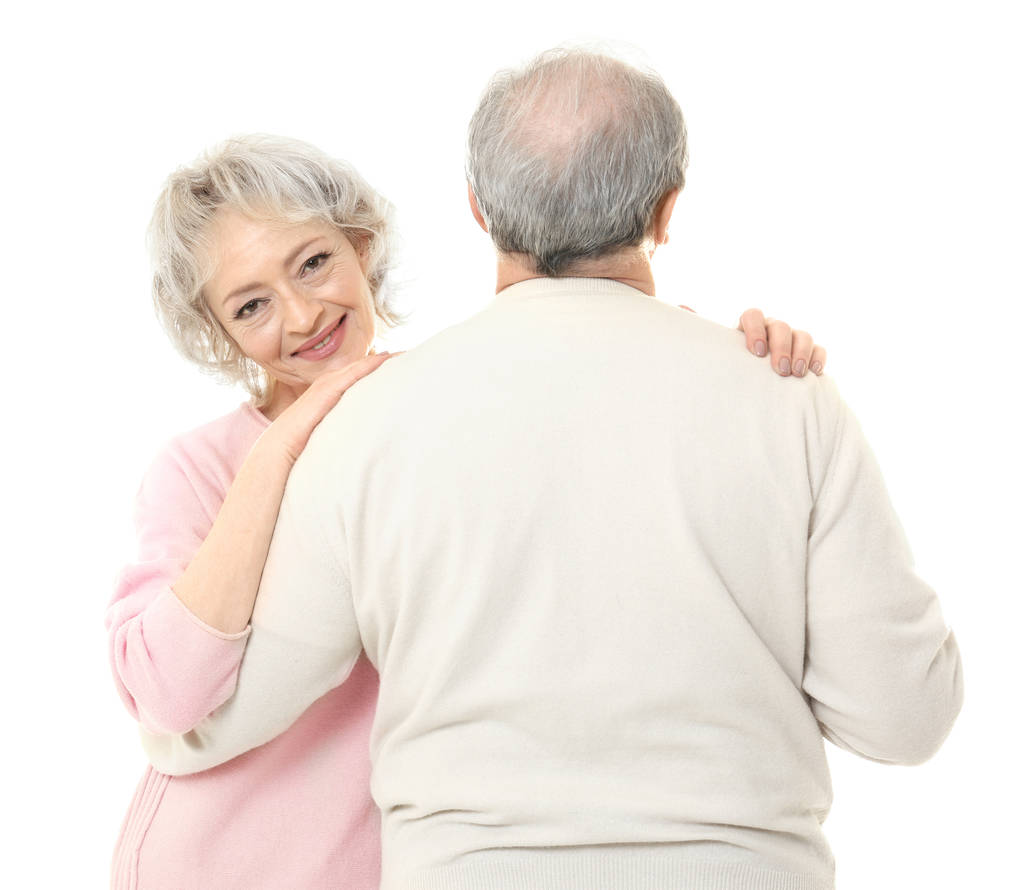 Mulher sênior feliz abraçando seu marido no fundo branco
 - Foto, Imagem