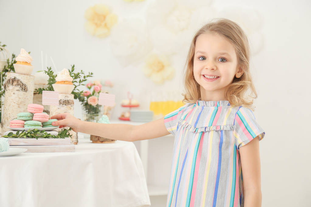 Симпатична дівчина біля столу з цукерками, поданими на вечірку
 - Фото, зображення