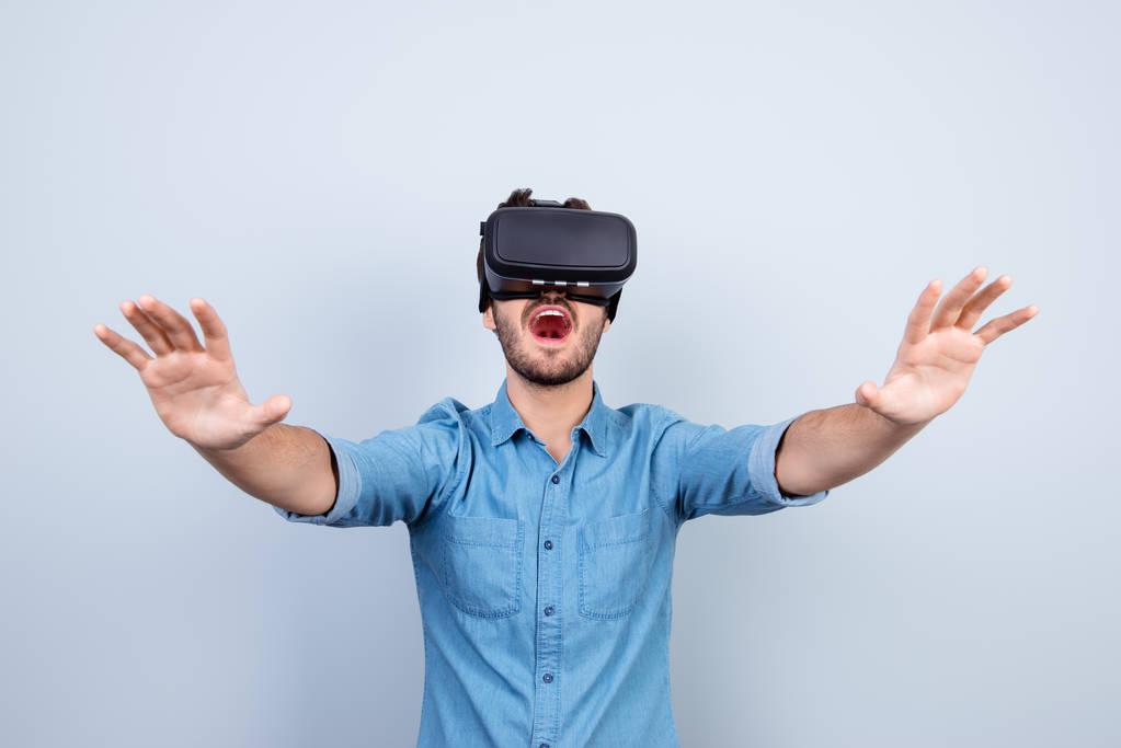 Excited young man is getting experience using VR-headset glasses - Photo, Image