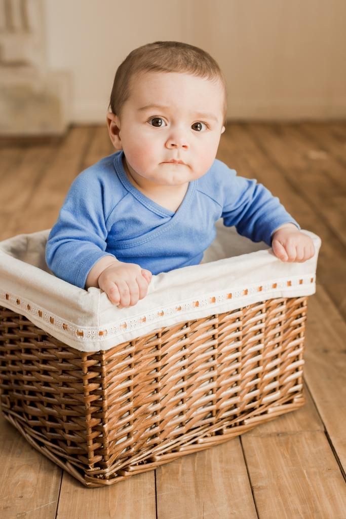 Дитячий хлопчик сидить у плетеній коробці
 - Фото, зображення