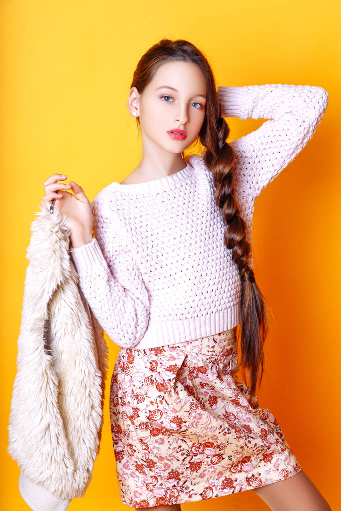 schöne niedliche Mode Mädchen Teenager in einem Pullover und einem Rock auf gelbem Hintergrund mit langen Haaren posiert - Foto, Bild