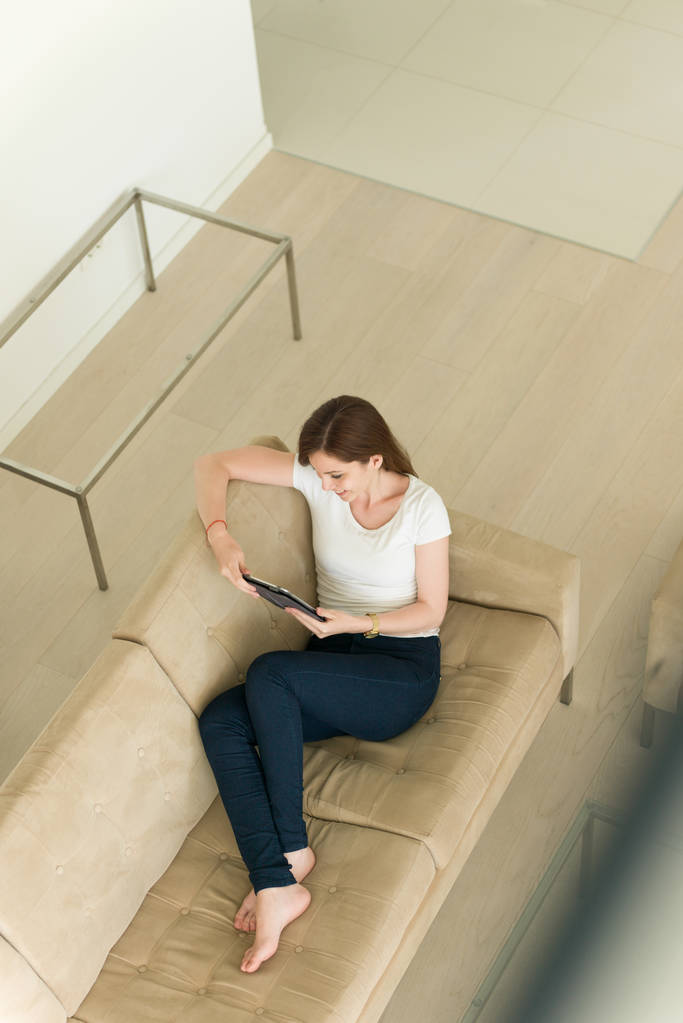 γυναίκα στον καναπέ χρησιμοποιώντας το tablet υπολογιστή - Φωτογραφία, εικόνα