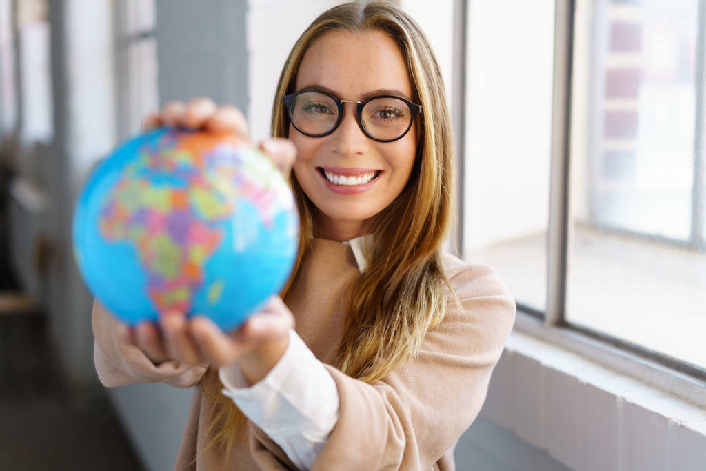 Smiling happy businesswoman holding up a globe - Photo, Image