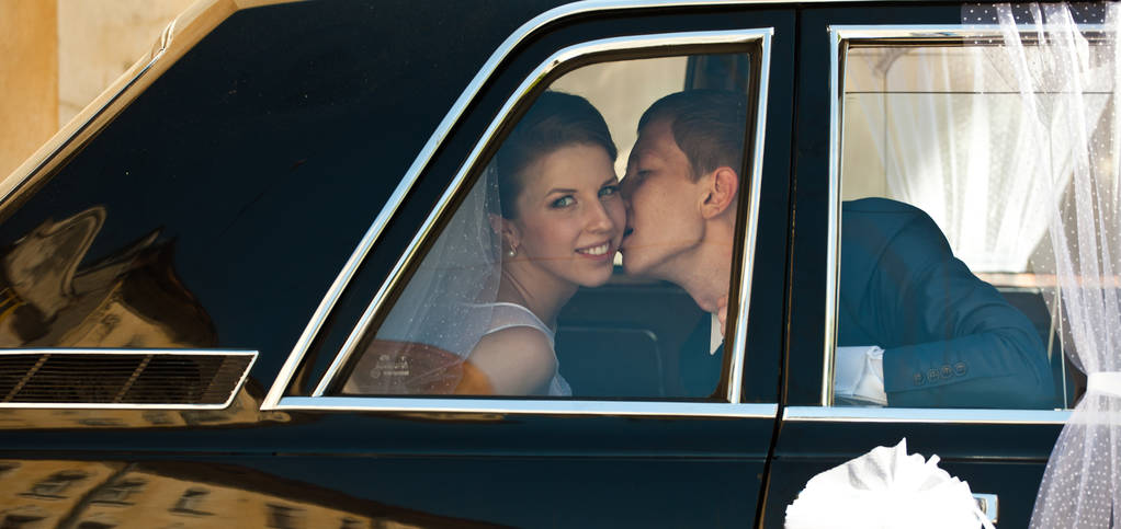 noivo beija bochecha da noiva sentado na limusine
  - Foto, Imagem
