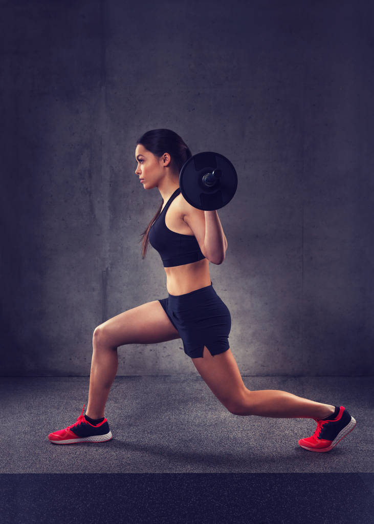 молодая женщина сгибает мышцы с штангой в спортзале
 - Фото, изображение