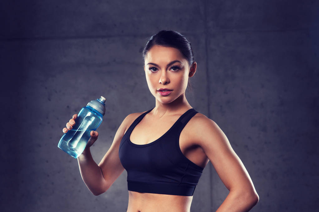 Mujer bebiendo agua de la botella en el gimnasio
 - Foto, imagen