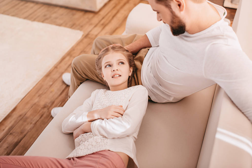 Rozkošná holčička s šťastným otcem společně na gauči doma - Fotografie, Obrázek