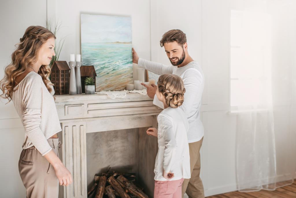 glückliche Familie hängt Bild des Meeres über dem Kamin zu Hause - Foto, Bild