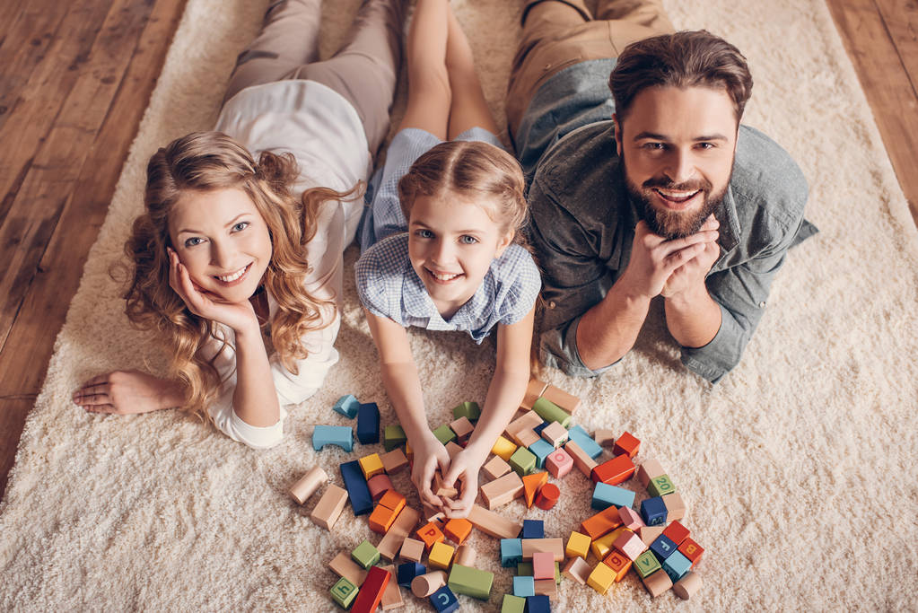 glückliche Familie spielt mit Bauarbeiter und liegt zu Hause auf dem Boden - Foto, Bild