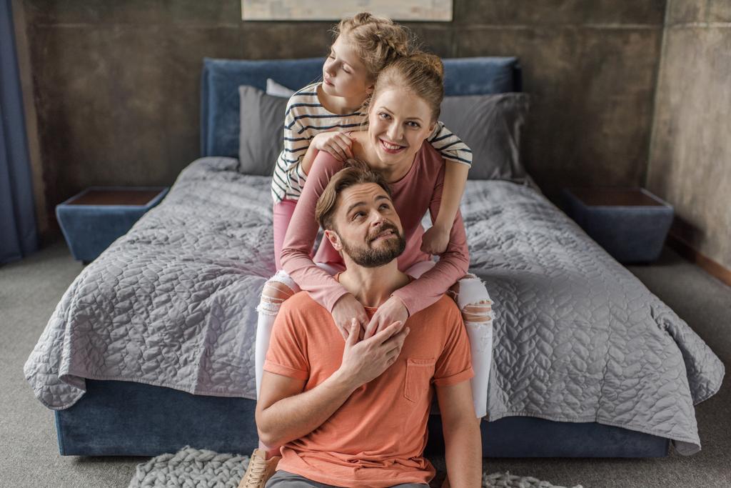 Mutlu genç ailesi ile birlikte oturma ve yatak odasında sarılma bir çocuk - Fotoğraf, Görsel