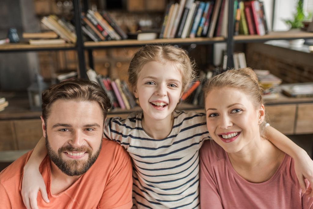 Happy young family with one child embracing and smiling at camera - Photo, Image