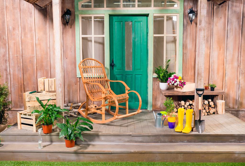 Plantes en pot et rocking chair sur le porche avec des outils de jardinage
 - Photo, image