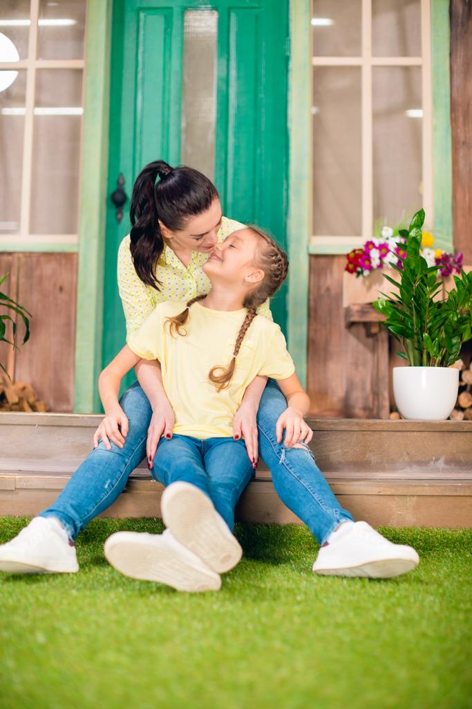happy mother and daughter sitting on porch and hugging outdoors - Photo, Image