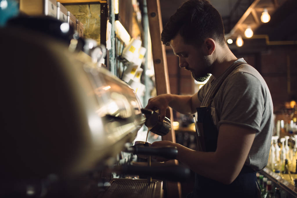 Młody mężczyzna barista przygotowanie drinka w ekspres do kawy - Zdjęcie, obraz