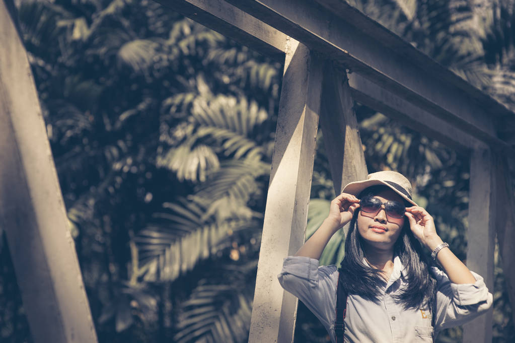 Όμορφη νεαρή ασιατική γυναίκα φοράει στρογγυλή καπέλο σε ένα πάρκο, ταξιδεύουν σε μια καλοκαιρινή μέρα - Φωτογραφία, εικόνα