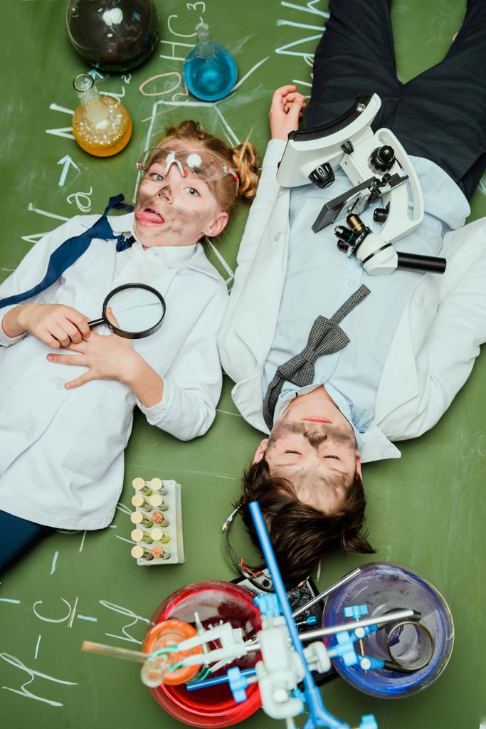 діти в лабораторних халатах лежать на крейдяній дошці
 - Фото, зображення