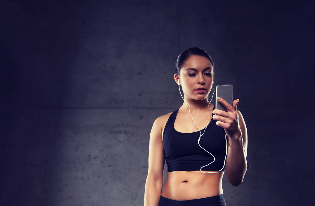 kobieta z smartphone i słuchawki w siłowni - Zdjęcie, obraz