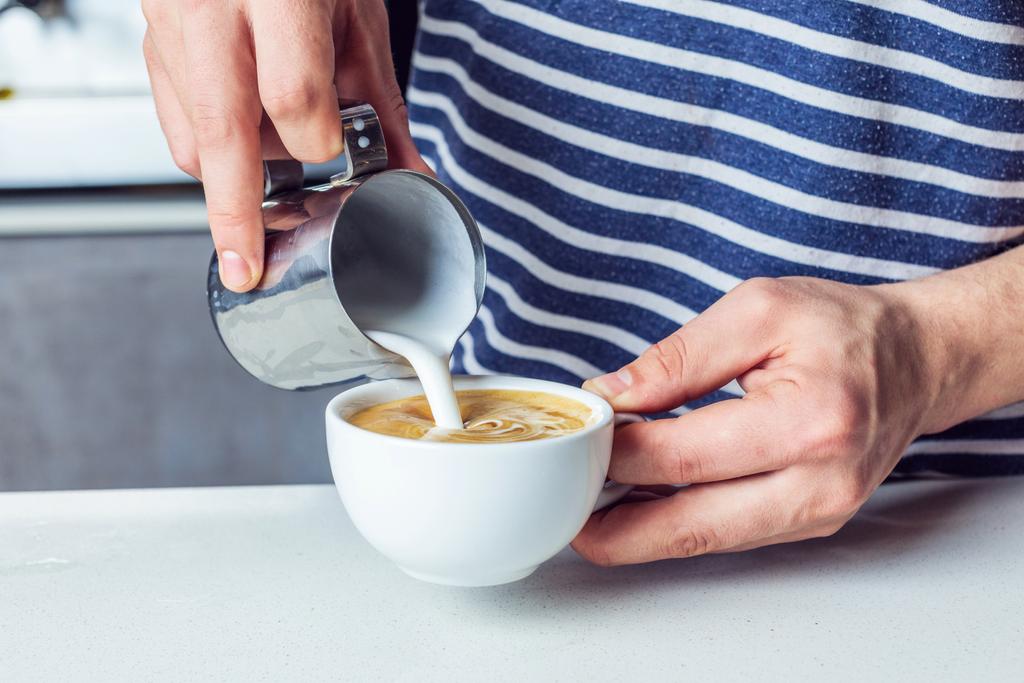 Человек наливает молоко в кофе - Фото, изображение