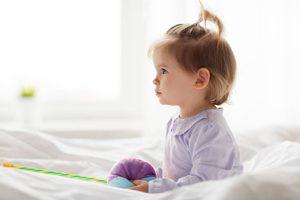 Υπέροχο μικρό κορίτσι με τα παιχνίδια στο κρεβάτι στο σπίτι - Φωτογραφία, εικόνα