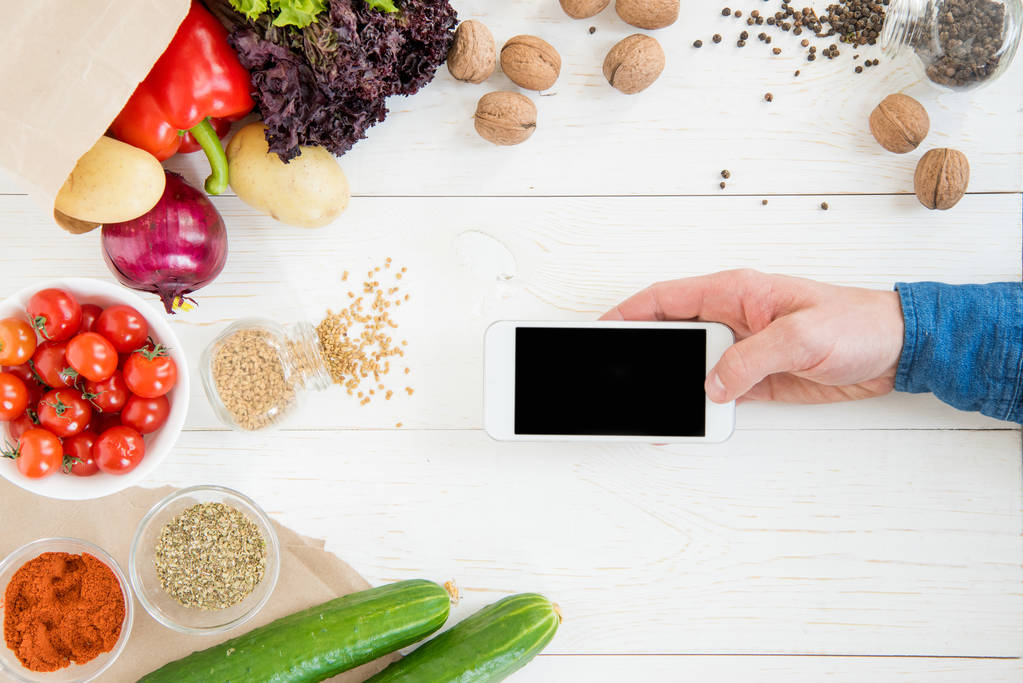 Особа, яка використовує смартфон під час приготування їжі
  - Фото, зображення