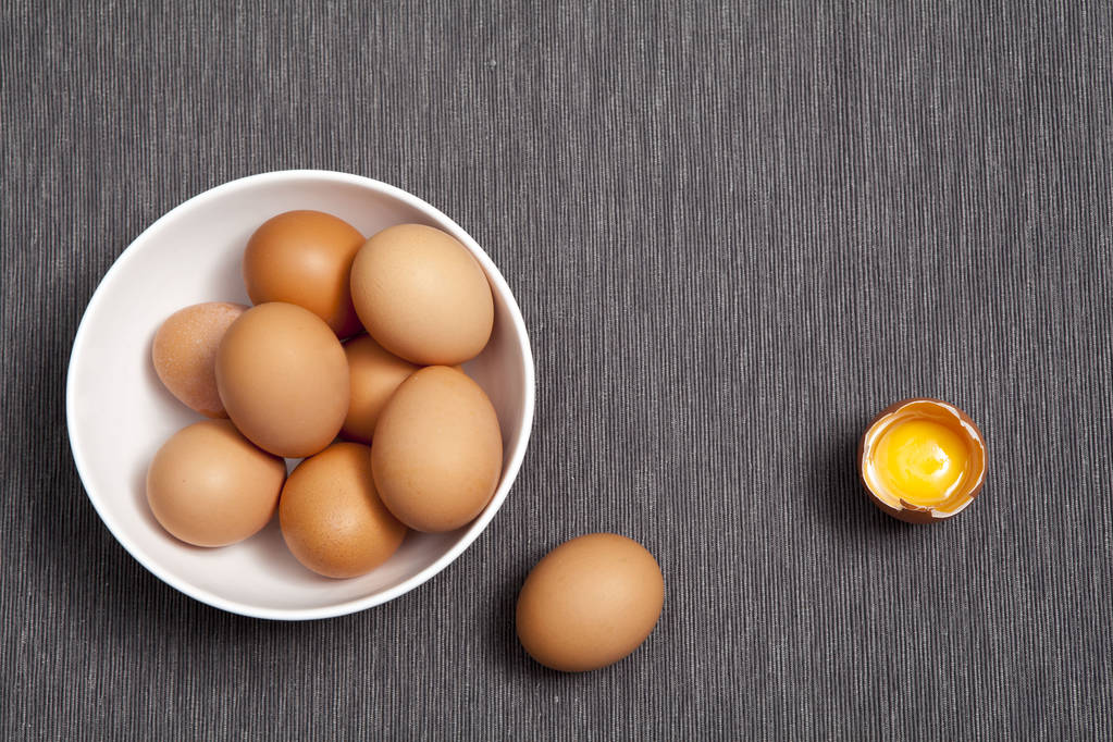 los Huevos en el plato blanco, un huevo entero junto al huevo roto en la mesa
 - Foto, imagen