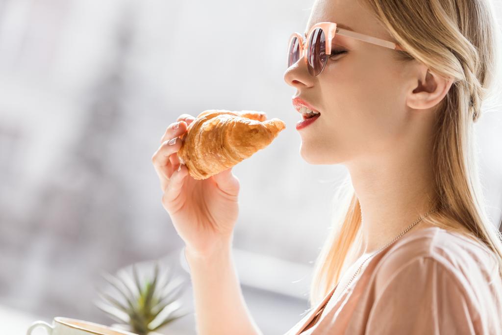 Jovem mulher comer croissant
 - Foto, Imagem