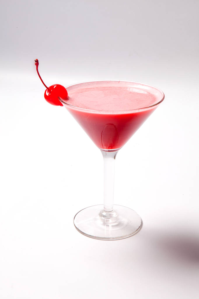 Červený nápoj v koktejlové skleničce, zdobený marachino cherry. na bílém pozadí - Fotografie, Obrázek