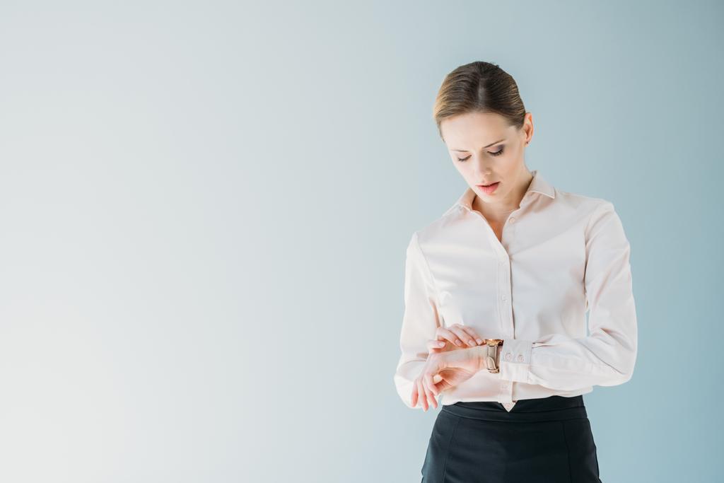 деловая женщина в формальной одежде смотрит на ручные часы
 - Фото, изображение