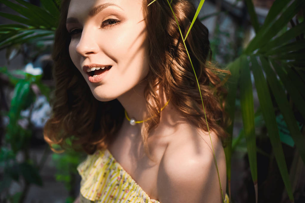 Retrato de cerca de la joven hermosa chica con pelo rizado vestido de verano amarillo en el bosque tropical
 - Foto, imagen