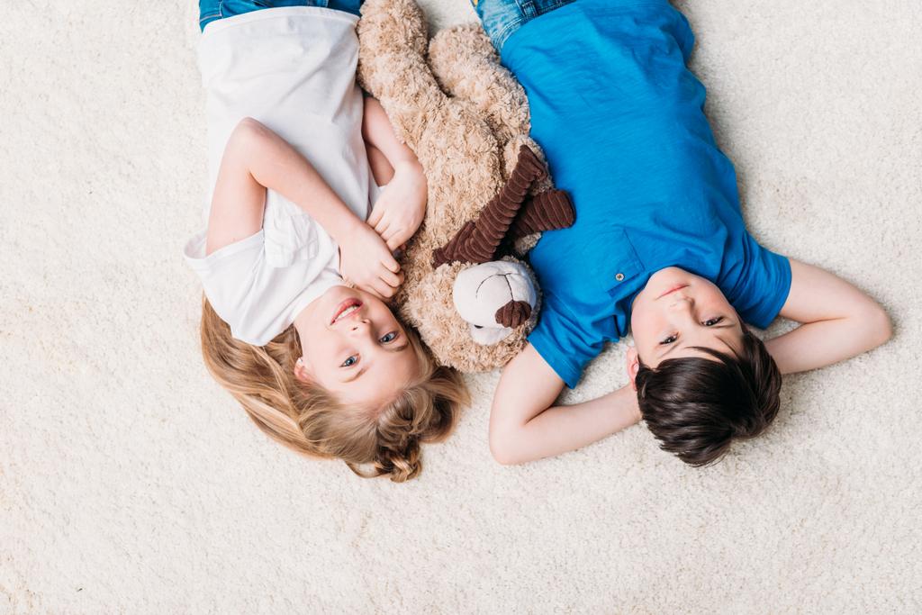 mały chłopiec i dziewczynka, leżąc na dywanie - Zdjęcie, obraz