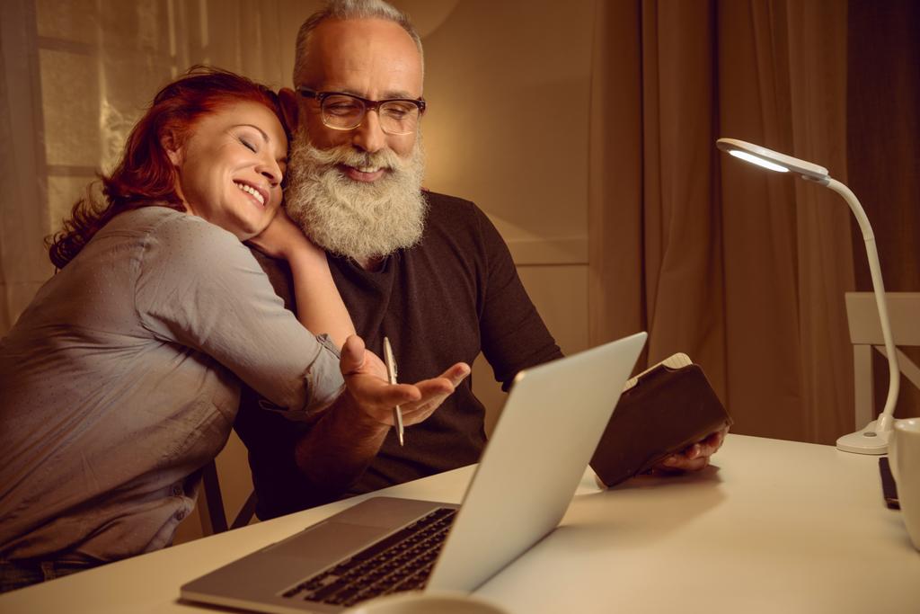 μέσης ηλικίας ζευγάρι κάθεται κοντά σε φορητό υπολογιστή - Φωτογραφία, εικόνα