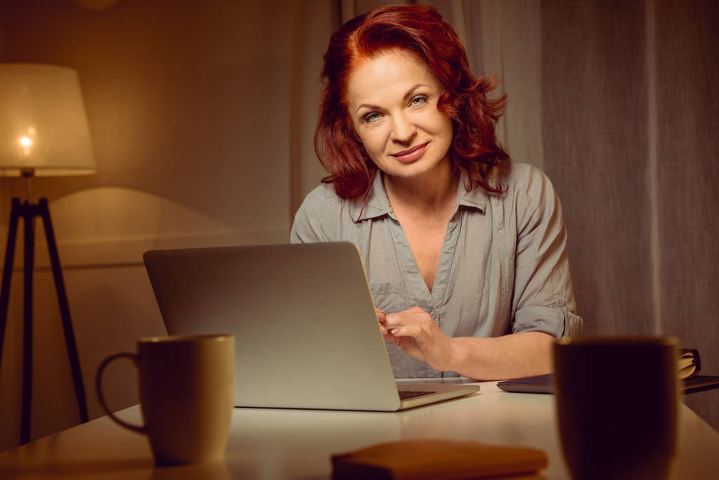 mujer trabajando en el ordenador portátil y mirando a la cámara
 - Foto, imagen